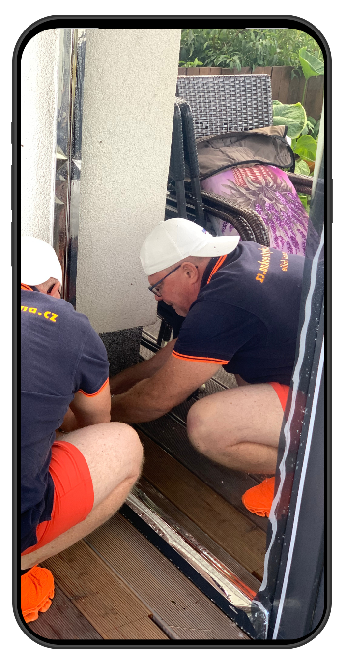 muž s bílou kšiltovkou aplikuje folii na okno